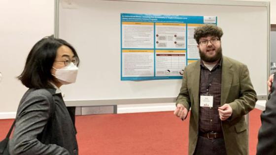 MLIS student Evan Dorman (right) talks about his research with visitors at a poster session.