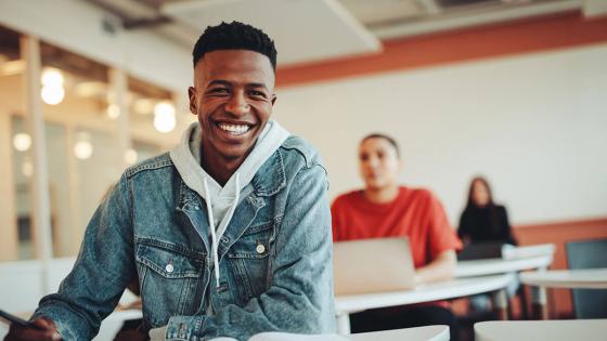 Smiling student seated at desk in classroom