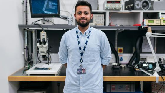 Engineering student standing in front of computers and lab equipment