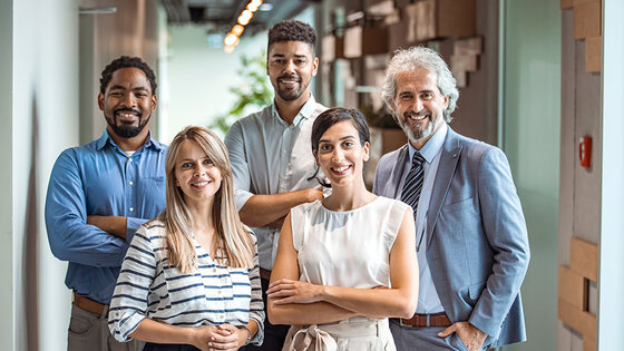 Coworkers pose and smile for a group photo in an office setting
