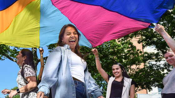 Woman smiling under a colorful parachute