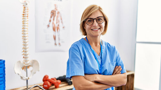 A kinesiology professional stands confidently in a clinic setting.