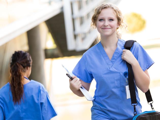 Nursing student with shoulder bag walking to class 