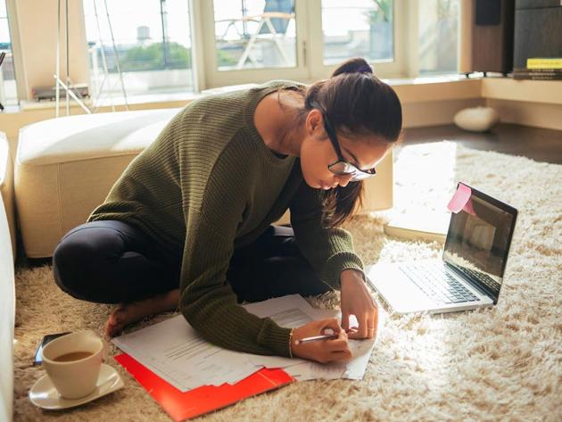 Woman sitting on floor with laptop and study notes
