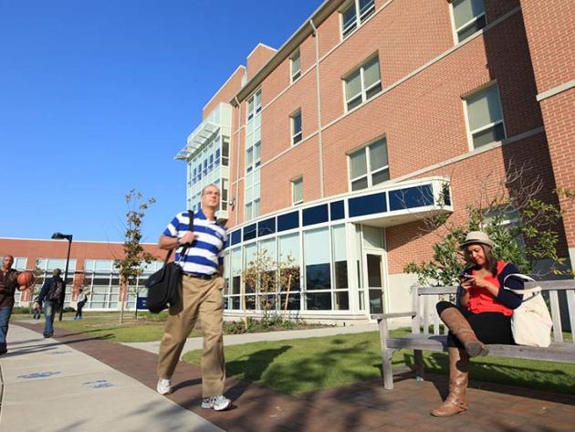 Students sit or walk outside a brick building on ODU's main campus