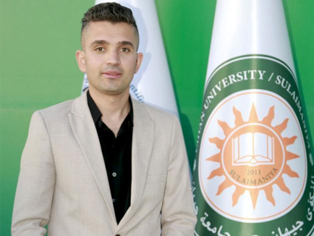 Photo of Sadiq Karim Omer standing next to a flag