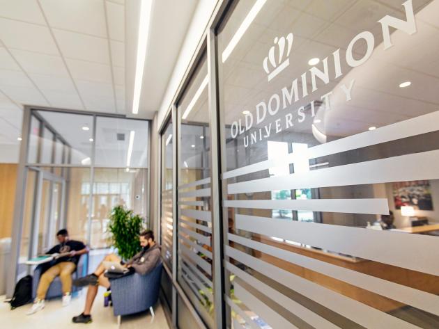 Old Dominion University logo on a glass window, with students seated and studying in the background.