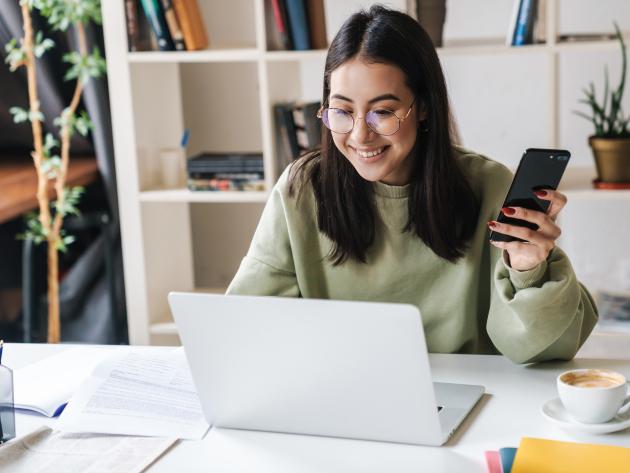 woman at computer with phone applying for college