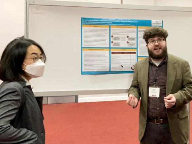 MLIS student Evan Dorman (right) talks about his research with visitors at a poster session.