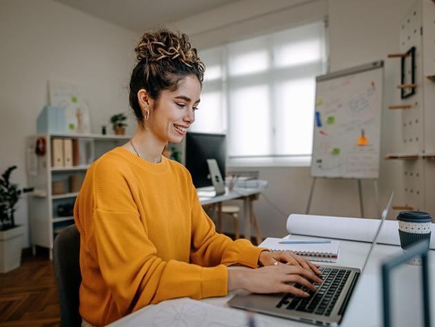 Woman sits at her computer searching for online degrees on ODUGlobal's website. Applying early can help ease your journey to online learning.